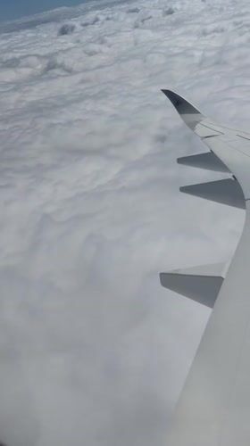 Passenger films wing view above clouds over Netherlands