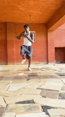 Two men dance on covered patio in Vom, Nigeria