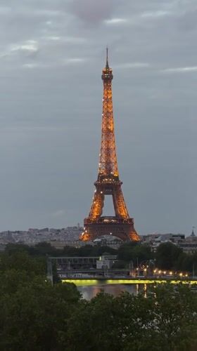 Eiffel Tower glows golden against cloudy Paris evening sky