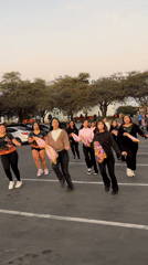 Flag-waving dance troupe rehearses at sunset in Arica parking lot