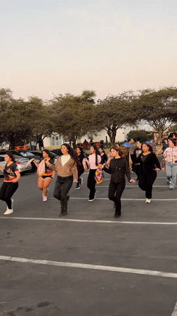 Flag-waving dance troupe rehearses at sunset in Arica parking lot