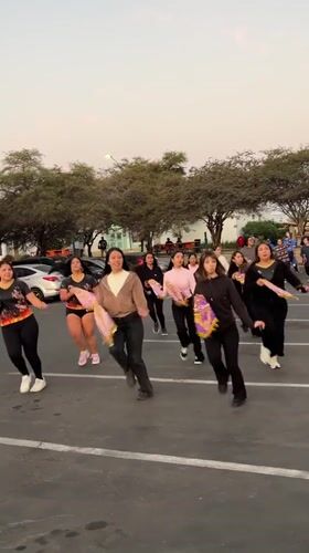 Flag-waving dance troupe rehearses at sunset in Arica parking lot