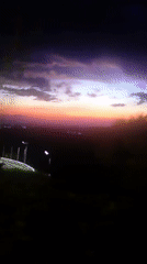 Storm-lit purple sky over water and open landscape at dusk