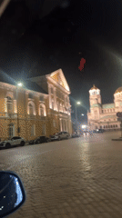 Nighttime drive past historic yellow building in Sofia captured