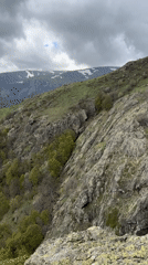 Hikers traverse rocky Bulgarian mountain terrain with waterfall, overcast conditions