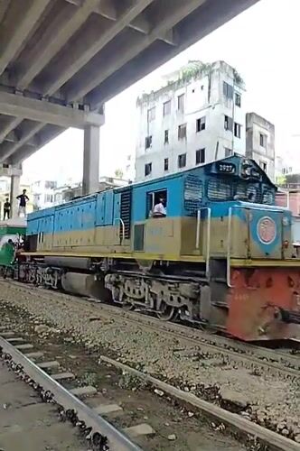 Trains pass under a bridge in Dhaka, riders on top