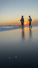 Two fishermen silhouetted against sunset on North Kuta beach