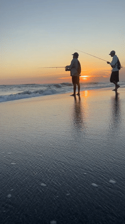Two fishermen silhouetted against sunset on North Kuta beach