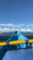 Three men travel by small blue boat in Indonesian waters