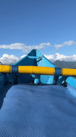 Three men travel by small blue boat in Indonesian waters