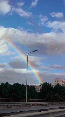Rainbow over Riga streets on a partly cloudy afternoon