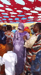 Daytime outdoor celebration held under decorated red canopy