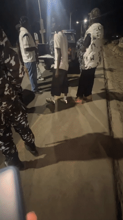 Nighttime roadside gathering with officers and civilians in Dam Camp
