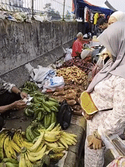 Street market buzzing with vendors, produce, and passing traffic