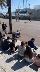 People gather on waterfront steps in Barcelona on sunny afternoon