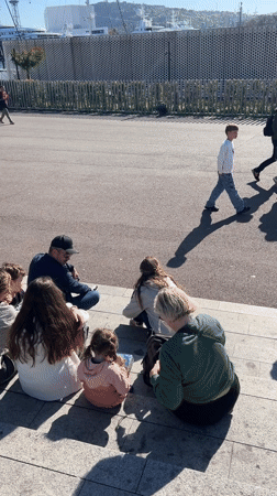 People gather on waterfront steps in Barcelona on sunny afternoon