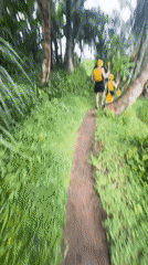 Person with kayak paddle walks muddy trail in Payangan