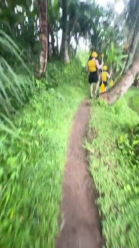 Person with kayak paddle walks muddy trail in Payangan