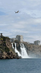 Aircraft flies over coastal waterfall near Antalya, Turkey