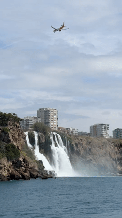 Aircraft flies over coastal waterfall near Antalya, Turkey
