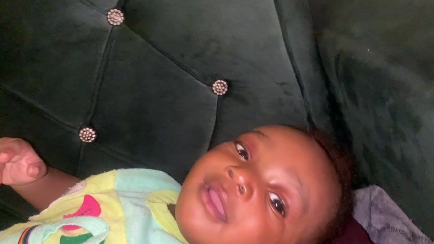 Baby smiles on green couch in Barakin Akawo, Nigeria