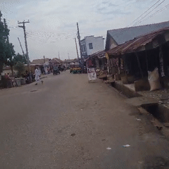 Rural street scene shows worn pavement, local shops
