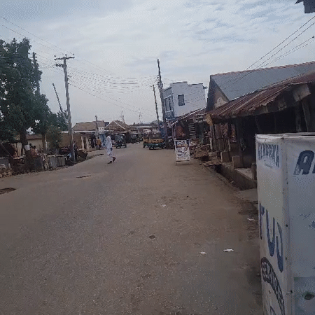 Rural street scene shows worn pavement, local shops