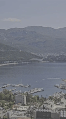 Aerial view documents coastal town nestled against green mountains
