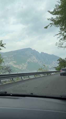 Car travels lakeside road toward Valerana, Italy