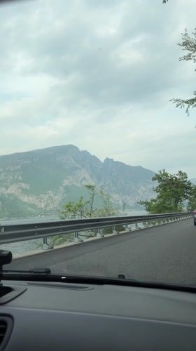 Car travels lakeside road toward Valerana, Italy
