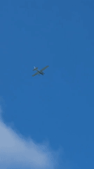 Morning beach scene with surfers and plane overhead in Netanya