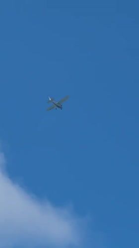 Morning beach scene with surfers and plane overhead in Netanya