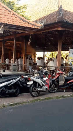 White-shirted group gathers under open roof in Gianyar