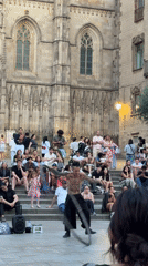 Street performer entertains crowd near Barcelona Cathedral at dusk