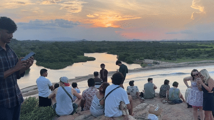 Group gathers on rocky coast to photograph sunset