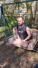 Man meditates on swing set in Russian backyard
