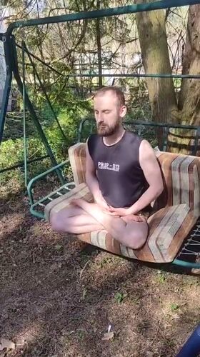 Man meditates on swing set in Russian backyard