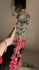 Person demonstrates seashell wind chime indoors in Kazanlak