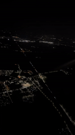 Aerial night footage captures illuminated Italian town from aircraft