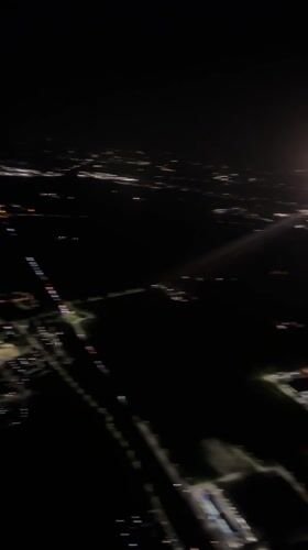 Aerial night footage captures illuminated Italian town from aircraft