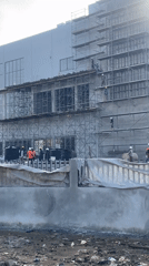 Multi-story construction underway in Abuja with workers and tuk-tuks on site