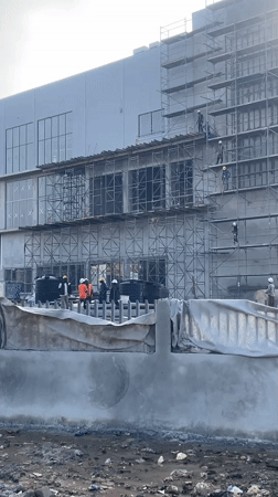 Multi-story construction underway in Abuja with workers and tuk-tuks on site