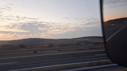 Dusk highway reflected in a side-view mirror, rural Spain