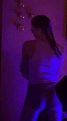 Two women dance under colored lights in Moscow room
