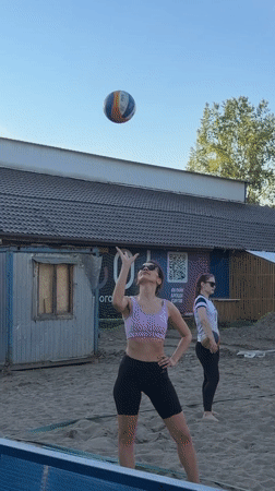 Woman practices beach volleyball in sunny Krasnoyarsk afternoon