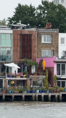 London riverfront houseboats and Shard tower observed under overcast skies