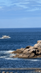 White motorboat cruises past rocky A Coruña coastline
