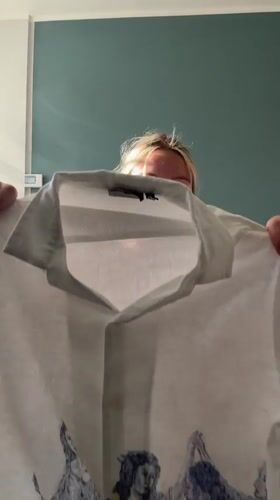 Woman displays white clothing item in Manchester living room