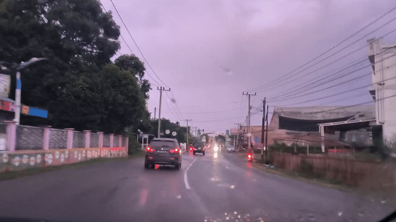 Vehicle travels wet road under overcast skies in Indonesia