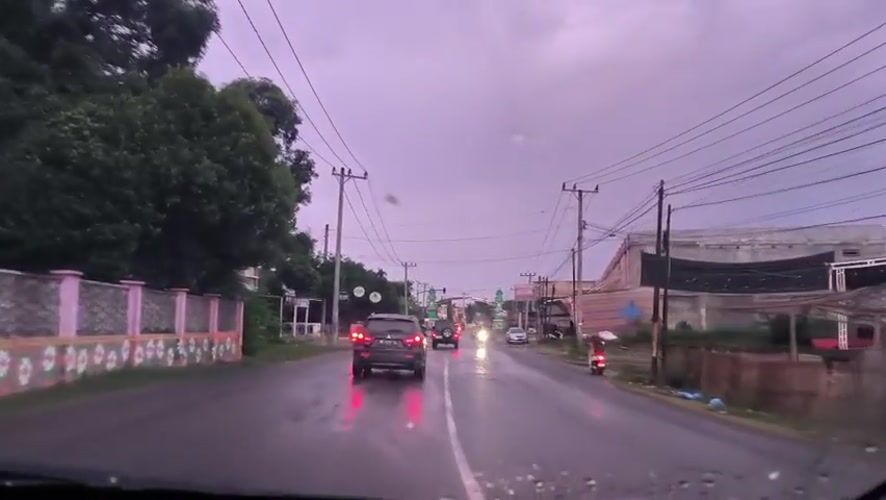 Vehicle travels wet road under overcast skies in Indonesia
